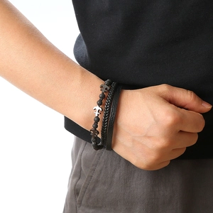 Detail showing a model wearing a black bead anchor bracelet and braided leather strap