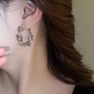 Close-up of a silver C-shaped butterfly earring featuring purple and clear zircons
