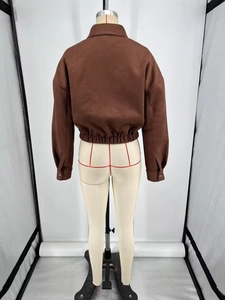 Detail view of the elastic waist hem and brown faux suede texture on the short jacket