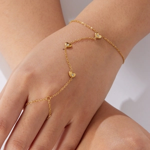 Elegant gold-plated heart finger chain bracelet with small rhinestones on female hand