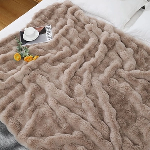 Close-up of fluffy camel faux fur blanket with wavy texture on a cozy white bed