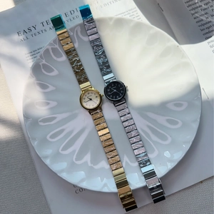 Detail of elegant gold and silver quartz watches with metal straps on a white plate