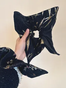 Detail of black jacquard fabric scrunchie with vintage gold and silver leaf patterns