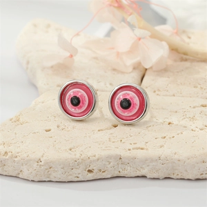 Vintage evil eye stud earrings with pink glitter resin in silver settings on a stone