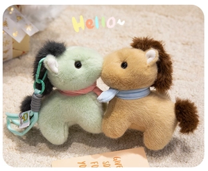 Detail of plush pony keychains in mint green and brown with scarves on a soft carpet