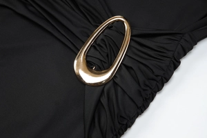 Détail de la boucle en métal doré sur tissu noir froncé d'une robe élégante