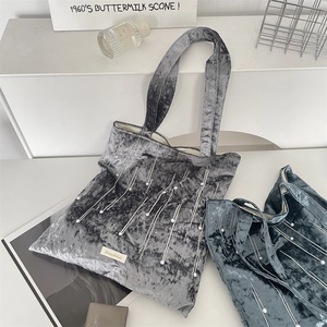 Close-up of velvet tote bag featuring pearl beads, contrast stitching and brand label