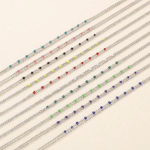 Silver cross chain necklace with multi-colored resin enamel beads on beige background