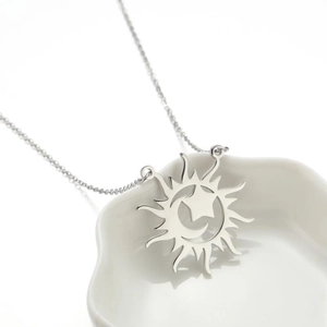 Silver sun and moon pendant necklace on a shell dish, long minimalist chain for women