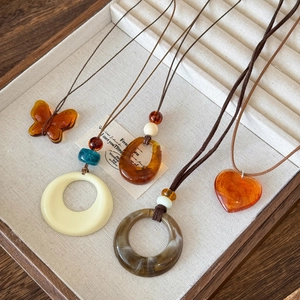 Retro resin geometric pendant necklaces with amber butterfly and heart on a jewelry tray