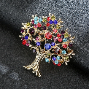 Macro view of a gold-plated Tree of Life brooch with multi-colored crystals on black leather