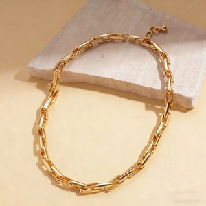 Detail of golden metal paperclip chain necklace with lobster clasp on natural stone base