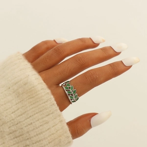 Detail of silver adjustable ring featuring green enamel leaf charms on hand