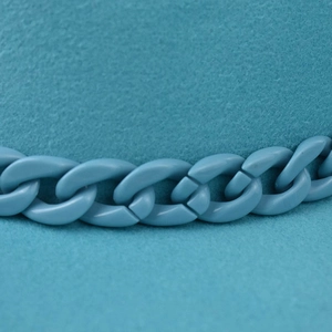 Close-up of a wide brim wool fedora hat featuring a matching teal plastic chain decor