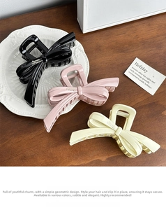 Close-up of elegant bow-shaped hair claws in black, pink, and cream on a wooden surface