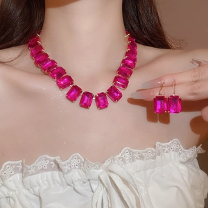 Close-up of luxury jewelry set with rose red square gemstones and gold necklace chains