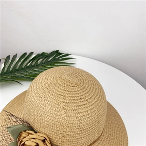 Detailed close-up of a woven straw hat with floral lace and a green ribbon bow