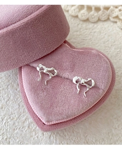 Close-up of S999 sterling silver bow earrings presented in a pink heart-shaped velvet box
