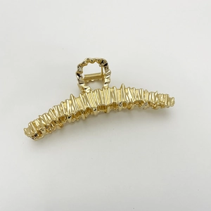 Detailed view of the gold irregular textured metal shark hair claw clip with glossy finish