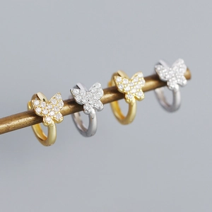 Macro shot of silver and gold butterfly hoop earrings with sparkling crystal pavé details