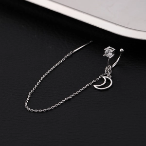 Macro detail of silver moon earrings featuring sparkling zircon and long chain tassels