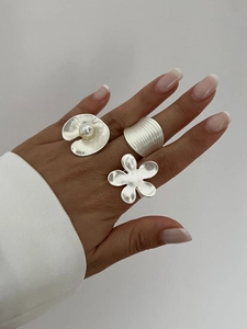 Detail view of brushed silver rings with pearl shell and abstract flower designs