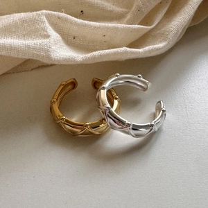 Detailed close-up of C-shaped rings with quilted pattern and studs in gold and silver