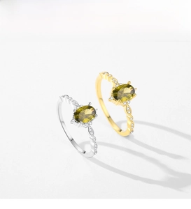 Detail view of gold and silver S925 rings with oval olive green stones and diamonds