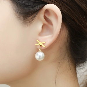 Detail of C-shaped stainless steel earrings with pearl drop on model's ear
