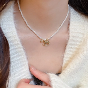 Detail shot of a pearl necklace featuring a delicate gold horse pendant on a model