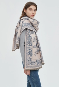 Detail view of soft beige scarf featuring blue paisley patterns and fringe tassels edges