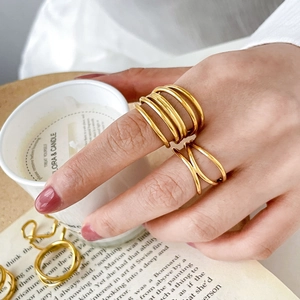 French style minimalist gold layered rings with interlaced wave patterns on fingers