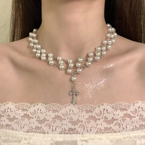 Detail of double-layer pearl necklace with a silver zircon cross pendant on a model neck