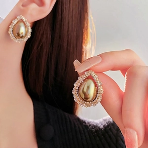 Elegant gold teardrop earrings with halo zircons and pearls on model for luxury fashion