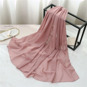 Detail of soft pink chiffon shawl hanging on a black metal rack over marble