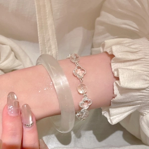 Detailed view of silver clover charm bracelet with clear beads on a woman's wrist