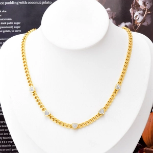 Golden Cuban chain necklace featuring five pavé-set diamond heart pendants on a neck model