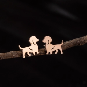 Macro detail of rose gold dachshund stud earrings on a natural wood branch