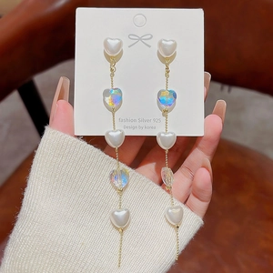 Detail of elegant heart tassel earrings featuring pearl and iridescent laser-cut beads