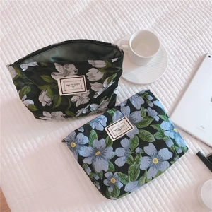 Flat lay of vintage floral jacquard canvas pouches with zippers on a white bed