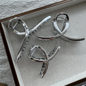Three elegant silver metallic shark hair clips with a high-gloss twisted design on a tray