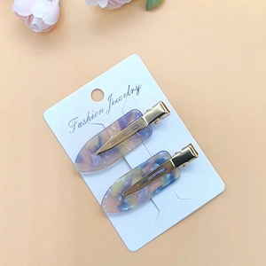 Detailed view of colorful acetate hair clips on display card with soft floral background