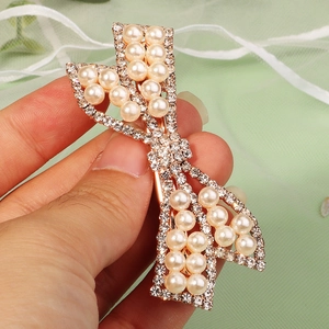 Macro shot of gold bow hair clip with sparkling rhinestones and delicate faux pearls