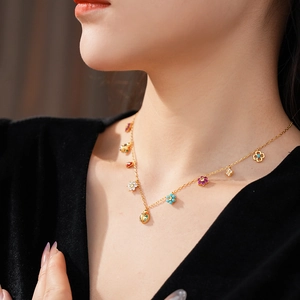 Close-up of golden necklace with colorful flower and ladybug charms on model's neck