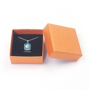 Orange textured gift box with sapphire necklace and ring set on black velvet interior