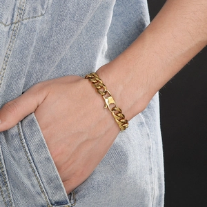 Gros plan d'un bracelet gourmette doré au poignet avec un design urbain minimaliste