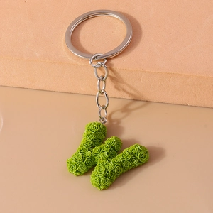 Detail of green letter W keychain with 3D embossed rose pattern and silver metal ring