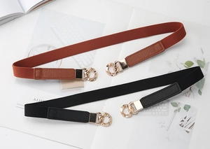 Detail of black and brown elastic waist belts with gold metal buckles on a magazine