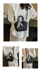 Close-up of black lychee grain leather bucket bag with geometric silk scarf and gold hardware