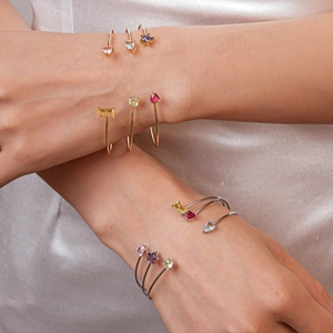 Détail de joncs superposés en or et argent avec zircons colorés en forme de cœur